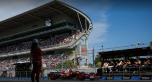 Monopost Ferrari projíždějící kolem hlavní tribuny na okruhu Circuit de Barcelona-Catalunya během Velké ceny Španělska.
