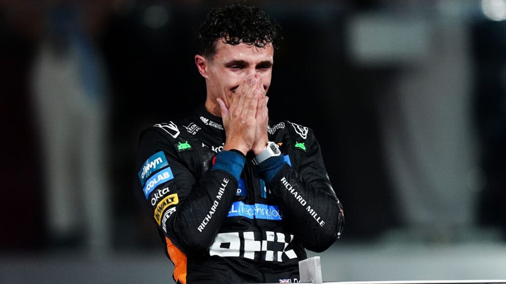 Emoce pilota Formule 1 bezprostředně po zisku titulu mistra světa v Abú Dhabí 2025. Pilot v týmové kombinéze si zakrývá ústa v nevěřícném gestu a šoku z vítězství.