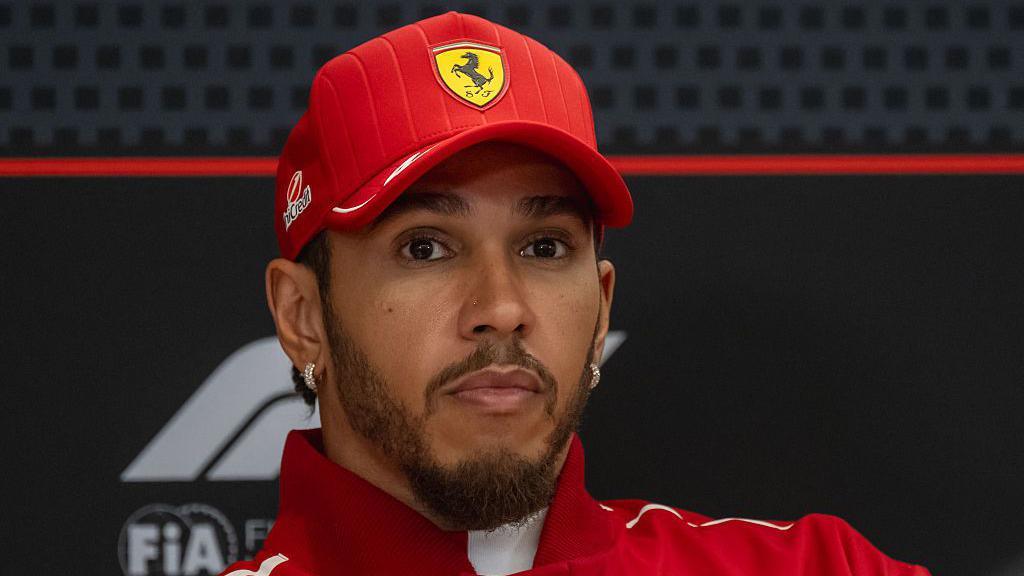 Lewis Hamilton v červené kšiltovce a týmovém oblečení Scuderia Ferrari